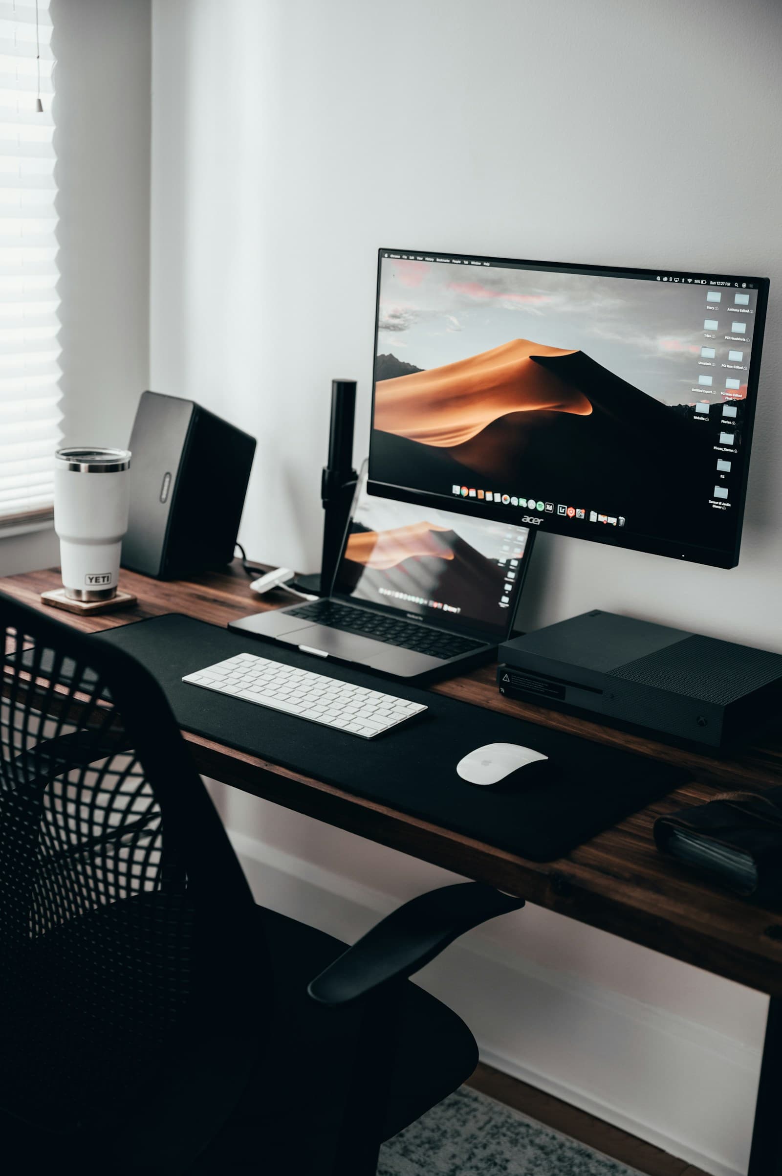 A computer and laptop on a wooden desk
